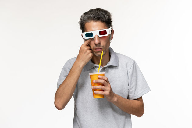耳机正面图：年轻男性在白色办公桌上喝苏打水 戴着d型太阳镜电影孤独太阳镜