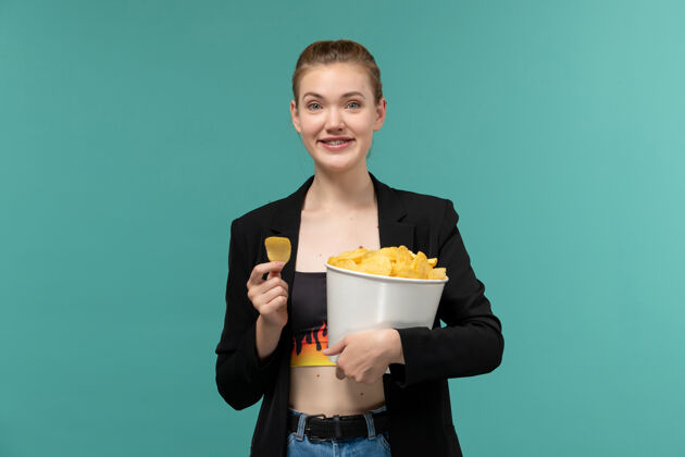 前台正面图：年轻的女性拿着薯片在蓝色的桌子上看电影抱年轻女性电影