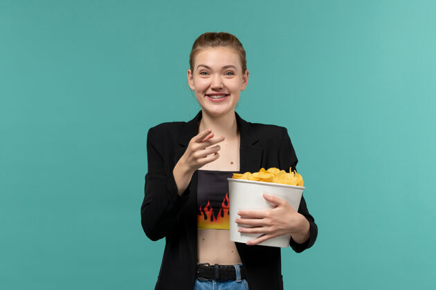 小吃前视图年轻女性在电影院吃薯片看电影在蓝色的表面服务员电影电影院