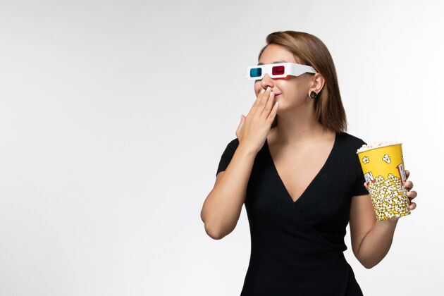 年轻的女性正面图白色表面上戴着d型太阳镜拿着爆米花的年轻女性女商人电影太阳镜