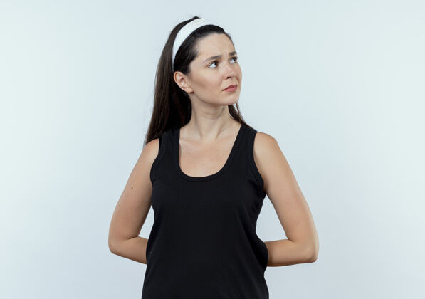 女人戴着头巾的年轻健身女站在白墙上 脸上带着沉思的表情望向一边年轻健康旁白