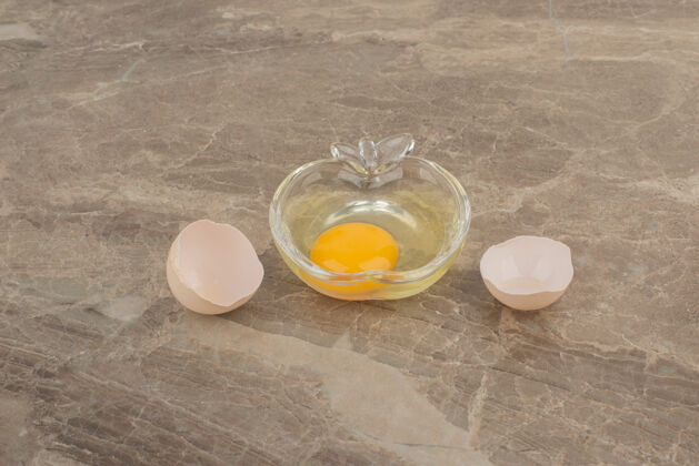 黄色碎鸡蛋放在大理石桌上的盘子上壳蛋黄顶部