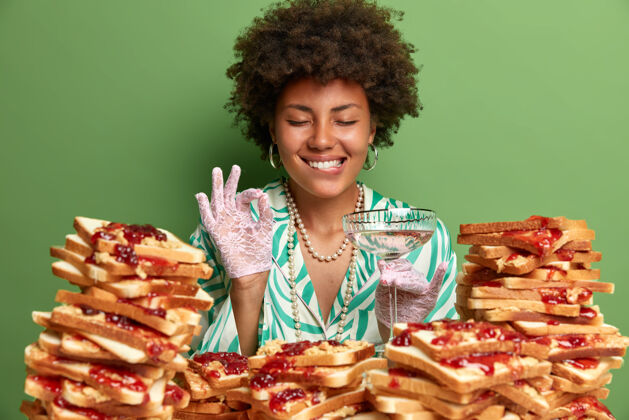 三明治迷人的女人 有着非洲头发 周围是花生酱果冻三明治人手套满意