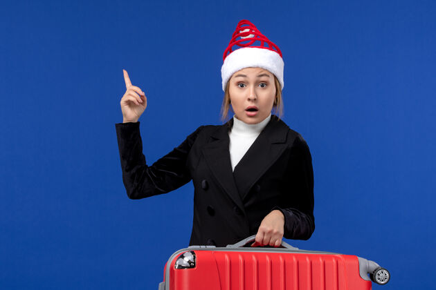 女人正面图：年轻女性提着红包在蓝色书桌上度假旅行女性度假年轻女性桌子圣诞节