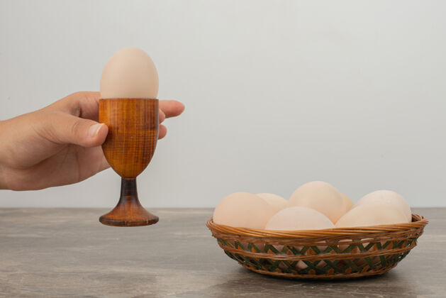 手手拿一杯鸡蛋和一篮子白鸡蛋大理石拿着篮子
