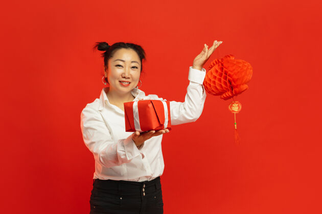 服装红墙上拿着灯笼和礼物的亚洲年轻女子中国人闪亮