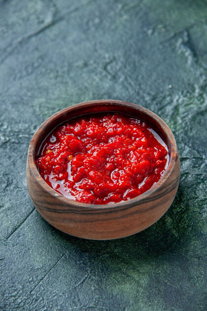 盐前视图番茄酱在深蓝色的桌子上棕色的盘子里番茄红色的调味料胡椒盐新鲜农产品番茄酱