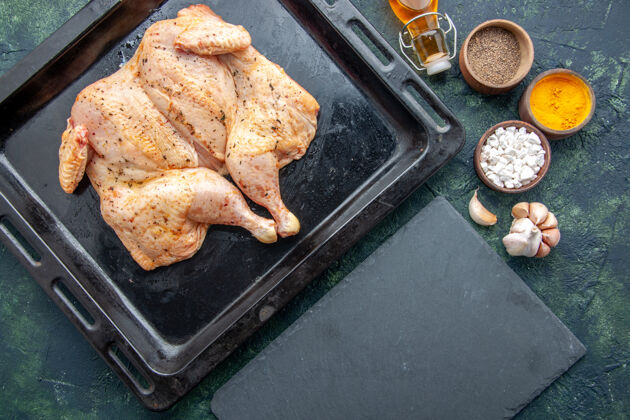 烘焙顶视图新鲜的五香鸡与调味料在深蓝色的背景下食物香料胡椒菜晚餐肉色盐烤抹刀膳食午餐