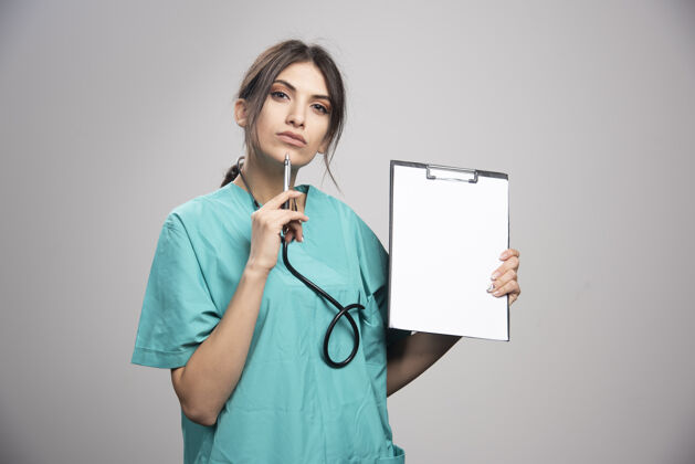 治疗女医生的画像摆在灰色的剪贴板上健康女性医生