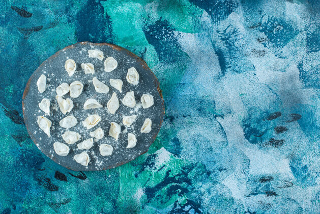 料理生的土耳其饺子放在板上 蓝色背景美味美味的碳水化合物