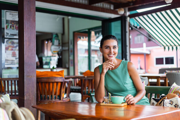 咖啡可爱 优雅 平静 快乐的女士 穿着绿色夏装 坐在咖啡馆里喝咖啡 享受早晨餐厅坐休闲
