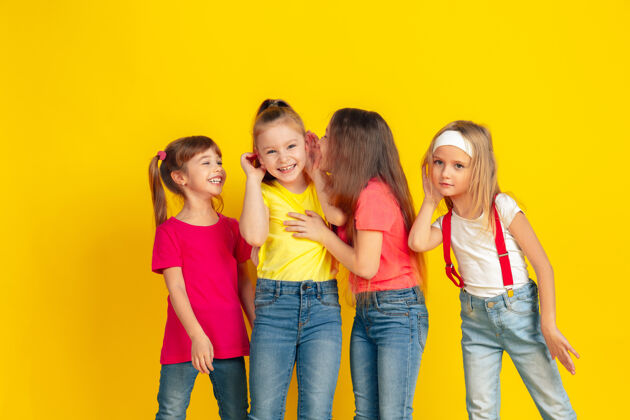 微笑秘密快乐的孩子们在黄色的工作室背景下一起玩耍和娱乐穿着鲜艳衣服的白人孩子看起来很好玩 笑 笑教育的概念 童年 情感童年欢呼人