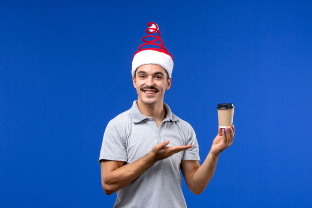 前面正面图年轻男子拿着咖啡杯在蓝墙上过年男子过节成人圣诞节光