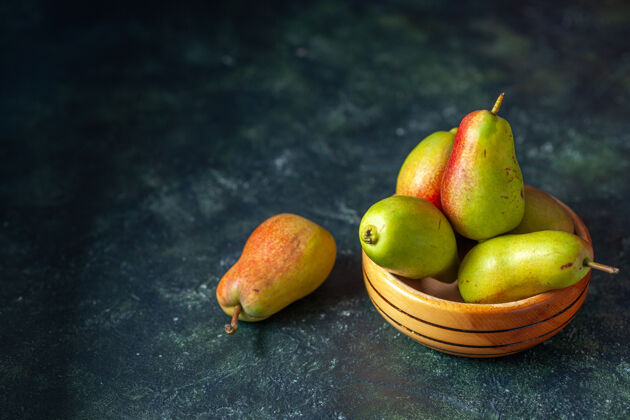 健康正面图深色背景上的甜梨成熟的果汁新鲜的苹果色盘子蔬菜木头