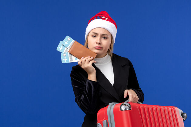 成人正面图年轻女性手持包和机票上蓝墙飞机度假飞机成功圣诞节