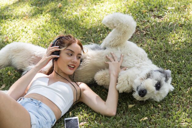 家养动物女人带着狗在户外听音乐科技耳机家养狗