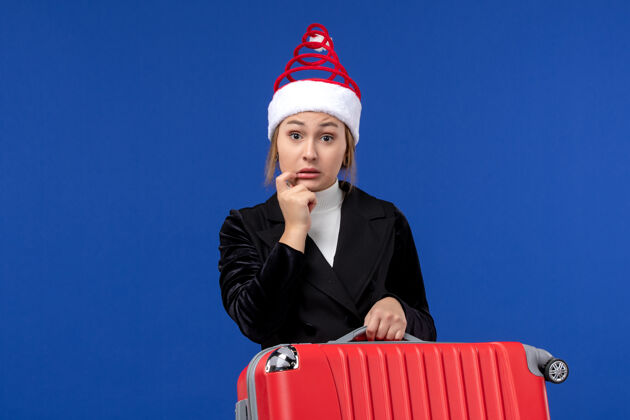 观点正面图年轻女子提着红包在蓝色地板上度假旅游的女人携带包公司
