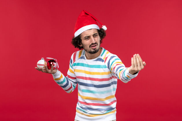 人正面图年轻人手持圣诞树玩具红墙假日红人新年年轻人玩具男
