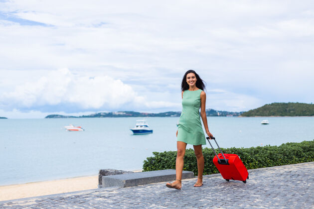 时尚快乐的白种人漂亮的长发优雅的旅游女人在酒店外面穿着红色的手提箱旅游旅游肖像