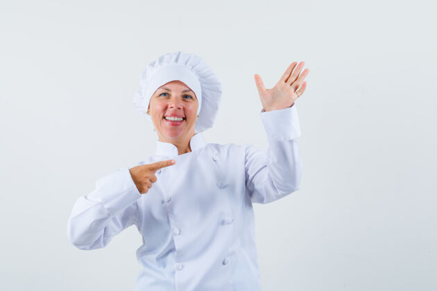 女人女厨师摆出一副像是指着手拿电话的姿势 穿着白色制服 看起来很专注魅力女士举行