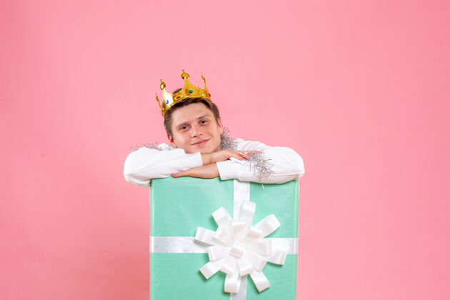 微笑正面图：年轻男性在粉色背景上戴着皇冠圣诞睡衣风景