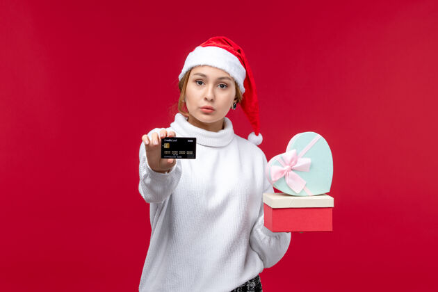 视图正面图红色背景上的年轻女性带着礼物和银行卡正面卡片成人