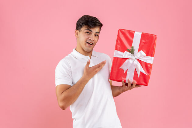 肖像正面图：年轻男性 粉色背景 圣诞礼物礼物微笑年轻男性