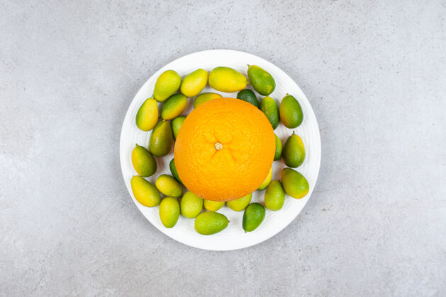 整个成熟的橘子和一堆金橘放在白色盘子里节绿色生的