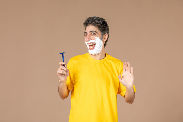 面部正面图：年轻男性在粉色背景上剃着泡沫脸成人淋浴肖像