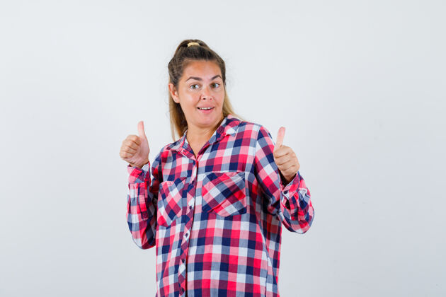 前面照片中的年轻女士穿着格子衬衫 向上竖起大拇指 看上去很快乐双人床成人脸