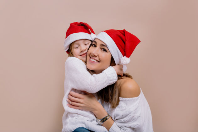 妈妈可爱的母亲和女儿戴着圣诞老人的帽子准备圣诞晚会的快乐家庭肖像惊喜圣诞帽孩子