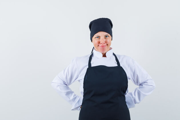 腰穿着黑色厨师制服的金发女人 手放在腰后 看起来很漂亮抱烹饪水疗