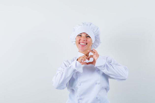 休闲身着白色制服的女厨师展示心形 看上去很欢快时尚心制服