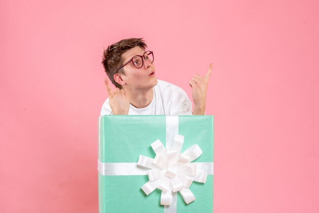 睡衣正面图：穿着白色衬衫的年轻男性 粉色背景的礼物圣诞节年轻男性指向