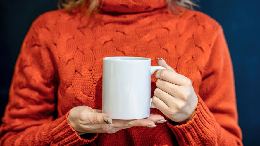 按摩穿着橙色毛衣的女人双手捧着一个白色的杯子 马克杯漆器茶