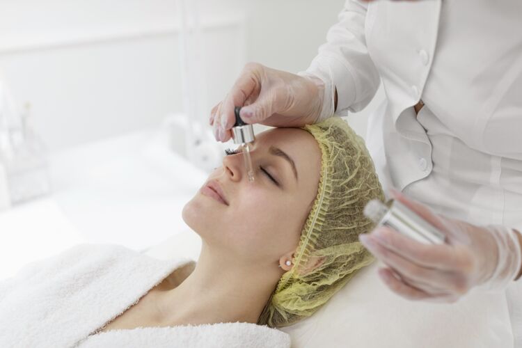 面部护理在美容诊所做面部护理的女人美容常规血清化妆品