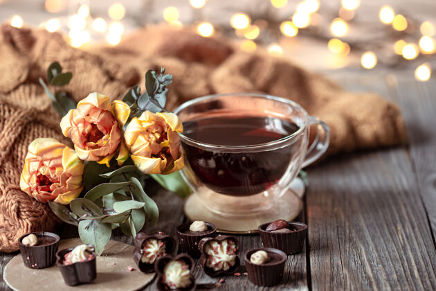 浪漫节日静物与一杯饮料 巧克力和鲜花在一个模糊的背景与波基装饰礼物针织元素