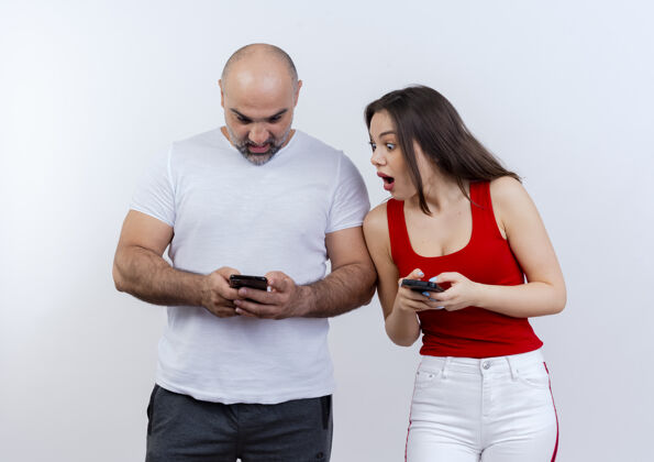 男人一对成年夫妇都拿着手机 男人看着他的手机 女人看着男人的手机 惊讶不已两者成人情侣