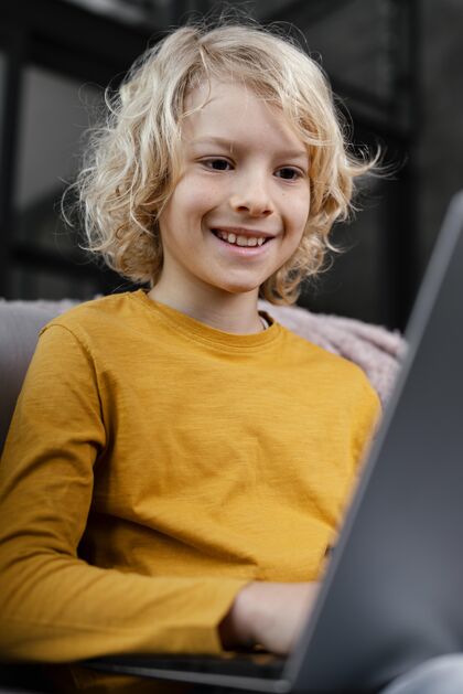 小玩意坐在沙发上拿着笔记本电脑的男孩设备房子男孩