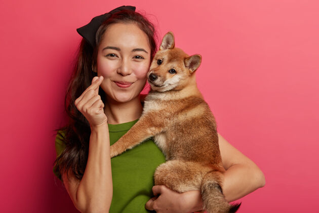 亚洲人美丽的亚洲女人的肖像展示迷你心手势 表达爱 拥抱日本血统的猎狗 享受与最喜爱的宠物共度自由时光友谊喜悦年轻人