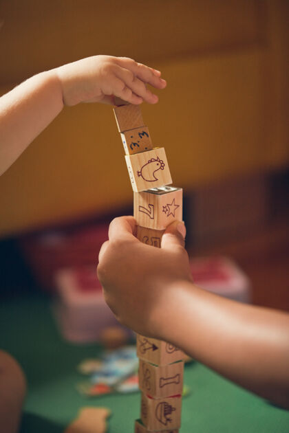 教育一个孩子和一个成年人在地板上玩教育木块的垂直镜头木头童年学校
