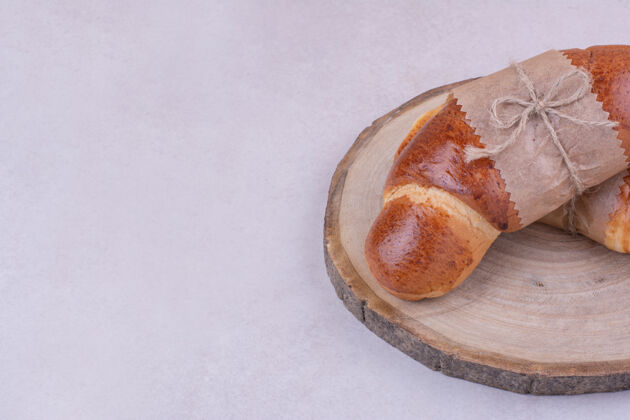 面粉羊角面包被隔离在灰色表面的木盘上艺术饼干甜点