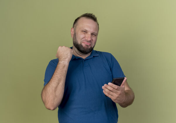 电话自信的成年斯拉夫男子手持手机握紧拳头绿色斯拉夫握紧