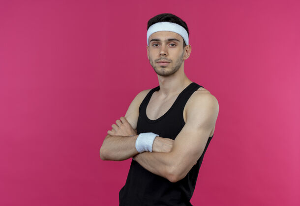 年轻戴着头带的年轻运动型男子 自信严肃的表情 双臂交叉放在胸前 粉色的上方交叉表情运动