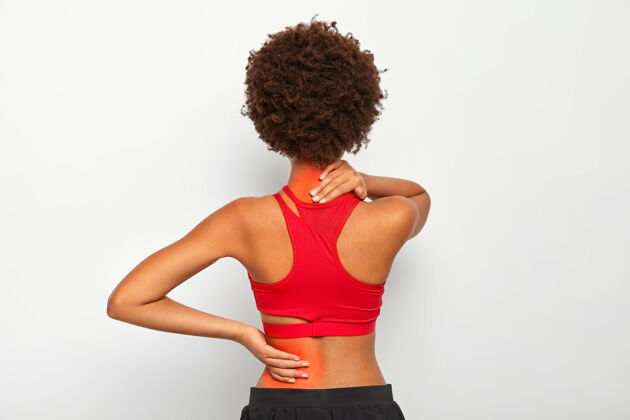 室内黑发女模特背部和颈部关节疼痛 有健康问题 穿着活动服隔着白色的工作室墙肌肉脖子按摩