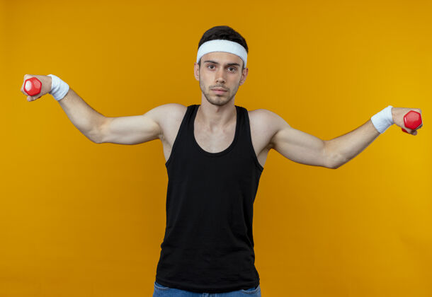 站立戴着头巾的年轻运动型男子 带着哑铃锻炼 严肃的脸庞凌驾于橙色之上头带哑铃年轻