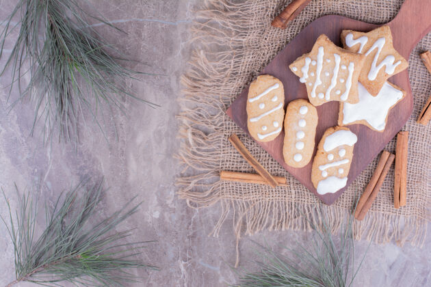 圣诞节圣诞姜饼呈椭圆形和星形 放在木板上 周围放着肉桂棒粗麻布饼干奶油