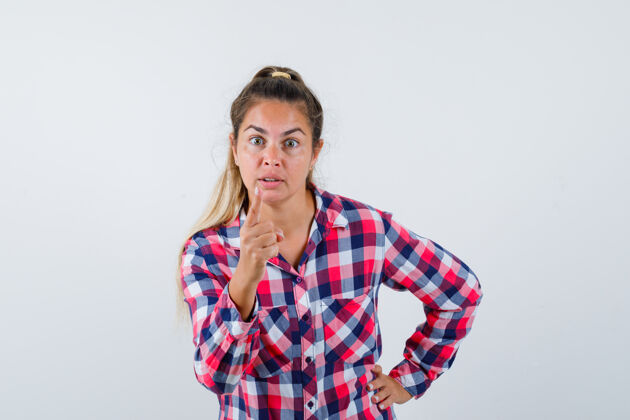 成人年轻女子的肖像警告与手指在休闲衬衫和看愤怒的前视图愤怒人衬衫