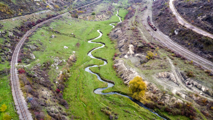 乡村无人机俯瞰摩尔多瓦的自然风光 溪流流进沟壑 山坡上有稀疏的植被和岩石 动车 多云的天空道路森林土地