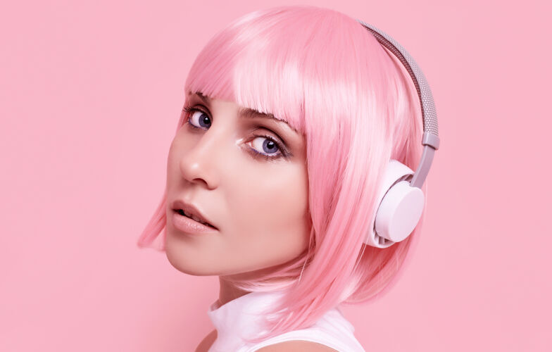 女人粉红头发的美女肖像在耳机里欣赏音乐模特快乐学生